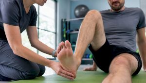 Patient doing knee extension exercise with therapist support