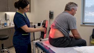 Clinic patient receiving red light therapy for back pain